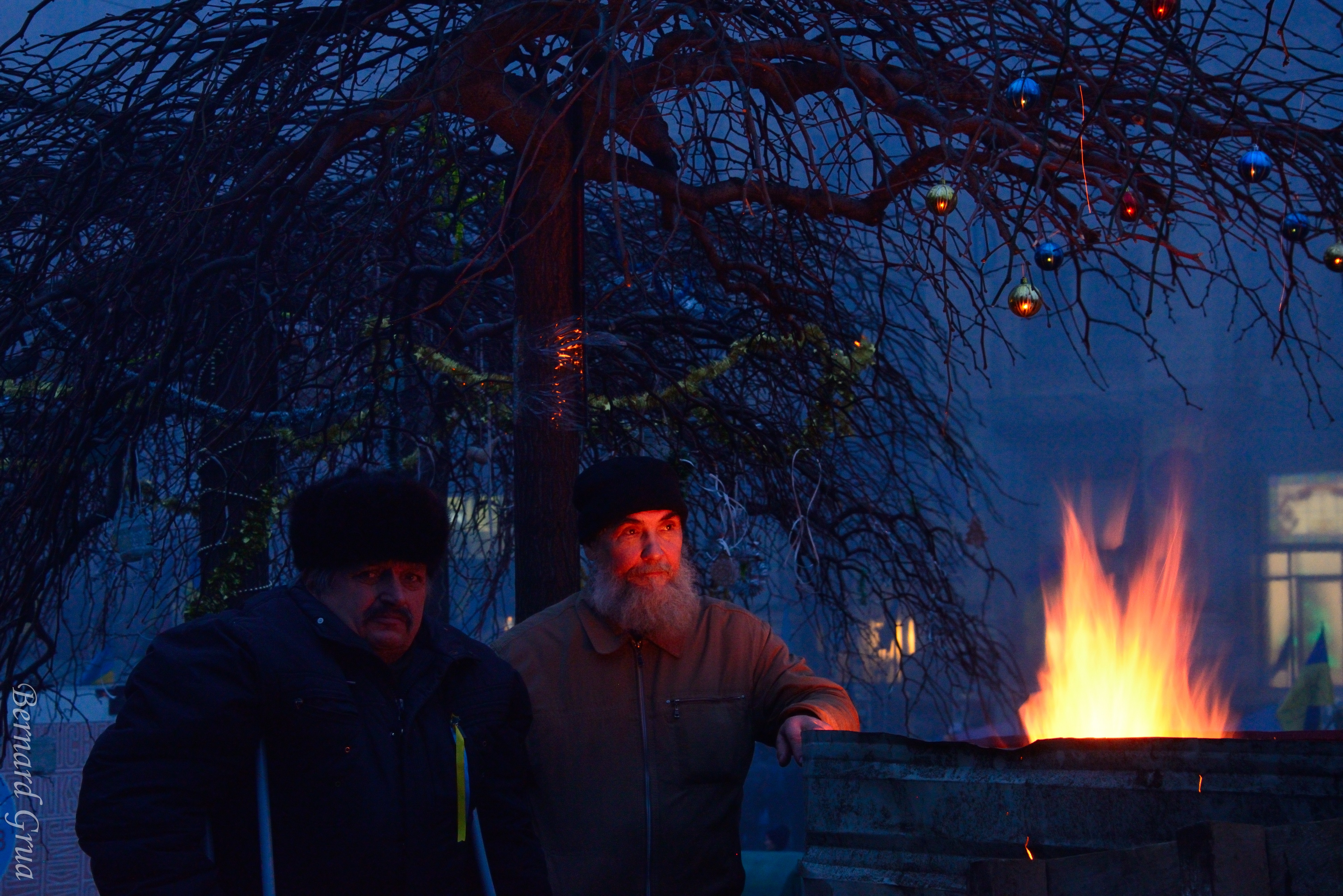 Maïdan, Kyiv, 31/12/2013, photo Bernard Grua DR
Commentaire de Pavlo Kuzyk, ami ukrainien: "Une autre de mes photos préférées. Le feu fournit un bel éclairage et des reflets sur les décorations du Nouvel An, et les visages des hommes reflètent leur inquiétude et leur incertitude quant à l'avenir du pays."