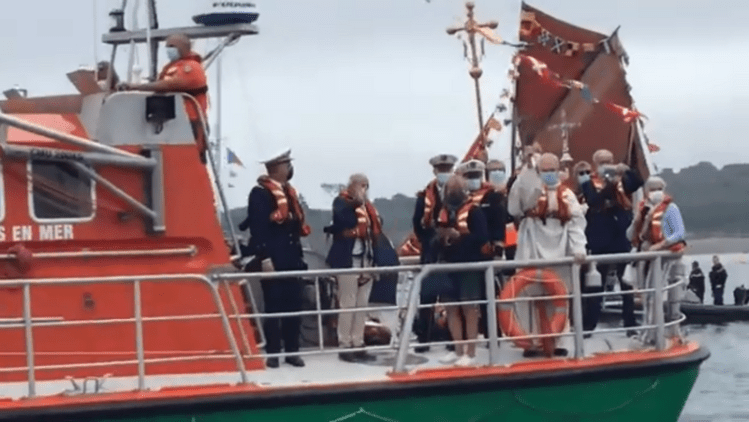 Благословення чайки «Пресвята Покрова» отцем Івоном Ле Ґоффом з борту рятувального судна. Ліворуч, адмірал у формі – знімок екрана з відео Олега Паньківа (див. нижче).